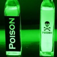 two bottles with skull and crossbones on them glow green in front of a black background