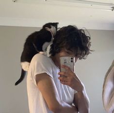 a man taking a selfie with a cat on his shoulder and another person holding a cell phone