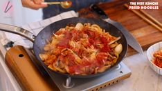 a person cooking food in a pan on top of a stove with chopsticks