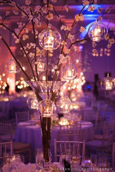 a tall vase filled with lots of glass balls and flowers on top of a table