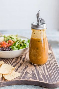 a bowl of salsa and tortilla chips on a cutting board with a salt shaker