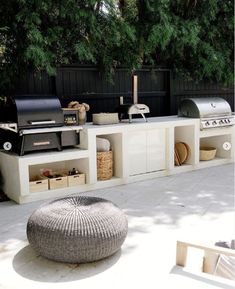 an outdoor bbq and grill area is shown in this backyard setting with large cushions on the floor