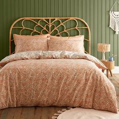 a bedroom with green walls and a bed covered in an orange flowered comforter