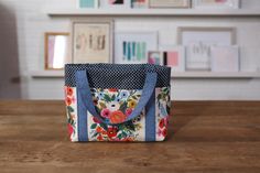 a bag sitting on top of a wooden table next to a wall with framed pictures