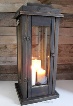 three lit candles sitting in an old fashioned lantern