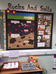 a bulletin board with rocks and soils on it next to some trays of food