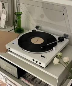 a record player sitting on top of a table next to a vase with flowers in it