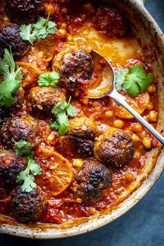 a bowl filled with meatballs covered in sauce and garnished with cilantro