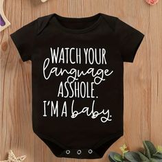 a black bodysuit with white writing that says watch your language ashole i'm a baby