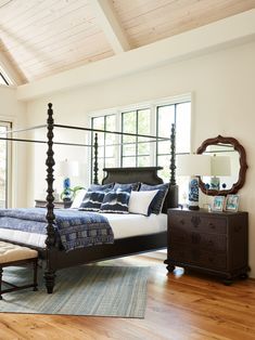 a bedroom with a four post bed, dresser and mirror on the wall above it