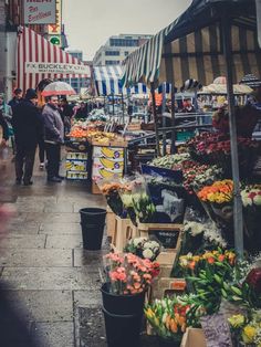 an outdoor market with people shopping and selling flowers