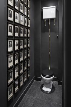 a black and white bathroom with pictures on the wall, toilet seat cover and roll of toilet paper