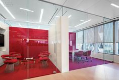 an office with glass walls and red chairs