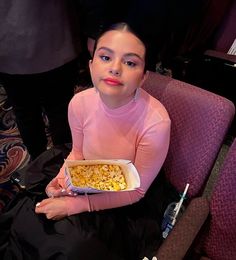 a woman sitting in a chair holding a box of popcorn