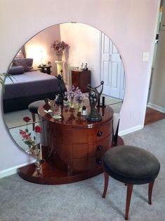 a mirror sitting on top of a wooden dresser next to a footstool in a living room