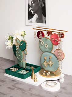 an assortment of jewelry sits on a table next to a vase with flowers in it