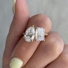 a woman's hand holding an engagement ring with three stones on the top and bottom