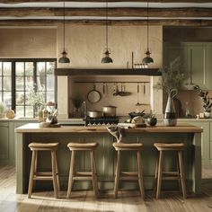 an image of a kitchen setting with stools in the middle and green cabinetry