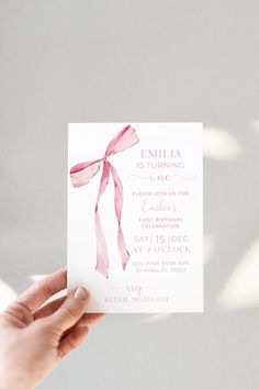 a person holding up a card with a pink bow on the front and back of it