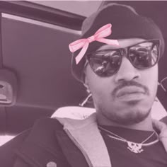 a man wearing sunglasses and a pink bow on his head sitting in the back seat of a car