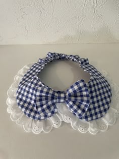 a blue and white gingham bow tie on a lace doily in front of a wall