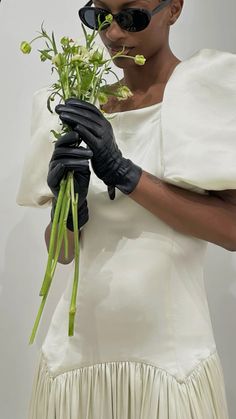 a woman wearing black gloves holding flowers in her hands