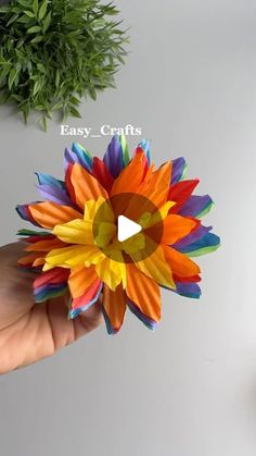 a person is holding a colorful paper flower