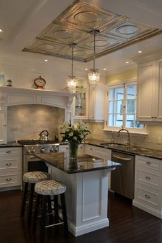 a kitchen with white cabinets and an island in front of the sink, stove top oven and dishwasher