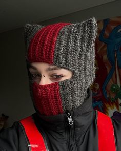 a person wearing a knitted hat with a red and grey striped covering over their face