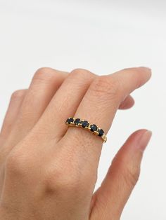 a woman's hand wearing a gold ring with three black stones on the band