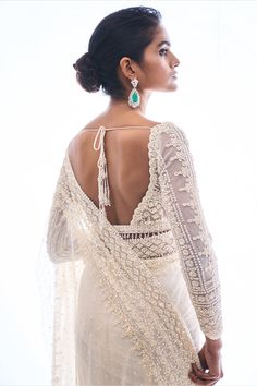 the back of a woman's white dress with sheer sleeves and beaded details