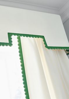 an open window with white curtains and green scalloped trim