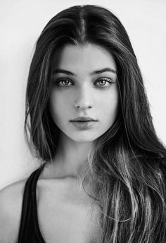 a black and white photo of a young woman with long hair looking at the camera