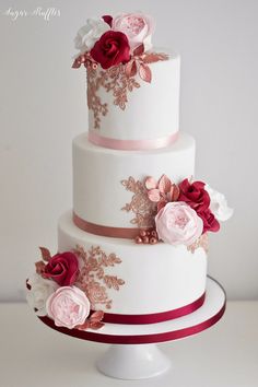 a three tiered wedding cake with pink and red flowers