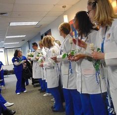 a group of women in white lab coats standing next to each other and holding flowers