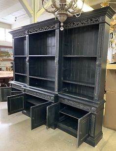 an antique black bookcase with drawers and chandelier