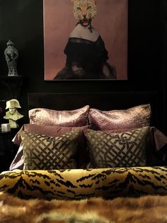 a bed with pillows and blankets in front of a painting on the wall