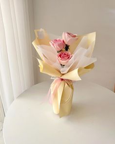 a bouquet of pink roses sitting on top of a white table next to a window