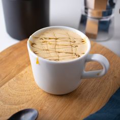 a white cup filled with liquid sitting on top of a wooden cutting board