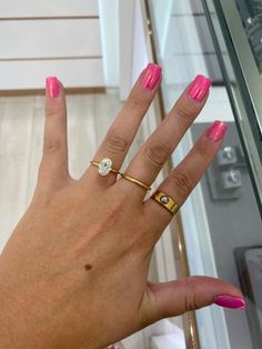 a woman's hand with pink nail polish and gold ring