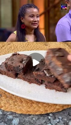 a man and woman standing in front of a plate of chocolate cake on the table