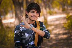 a young man with his hand up in the air while wearing a camo shirt