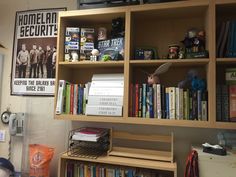 a bookshelf filled with lots of books next to a wall mounted clock and other items