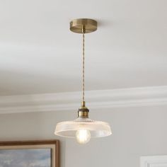 a light fixture hanging from the ceiling in a room with a painting on the wall