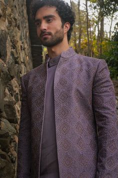 English Purple Contemporary Jacket | Jatin Malik Introducing The Kashmiri Jamawar Embroidered Open Sherwani Set in elegant English purple. Paired with a matching drape kurta featuring pintuck details and tapered trousers, this set exudes sophistication and timeless charm. Included in purchase: Short Jacket, Kurta, Trousers Product Specification Color: English Purple Fabric: Linen Silk Occasion: Engagement, Wedding, Bridal, Reception Style: Short Jacket, Kurta, Trousers Care: Dry Clean Customization options:Can be customized in any color or style Note: A stylist will contact you to confirm measurements after your order is placed.Estimated delivery time: 4 -6 weeks (Variation in color, fabric & detail is possible. Model images are only representative.) This can be customized in any color, si Open Sherwani, Jatin Malik, Collar Kurta, Indian Wedding Clothes For Men, Tapered Pant, Purple Linen, Dhoti Pants, Royal Look, Haldi Ceremony