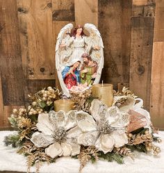 an angel figurine sitting on top of a table with candles and other decorations