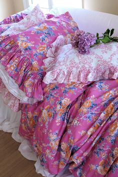 a bed with pink and orange floral comforter on it's side, next to a window