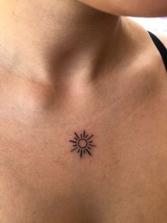 a woman's chest with a small sun tattoo on her left side ribcage