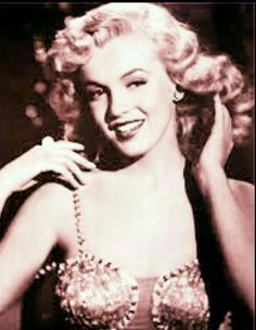 a black and white photo of a woman with blonde hair wearing a beaded bra