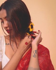 a woman holding a yellow flower in her right hand and wearing a red scarf around her neck